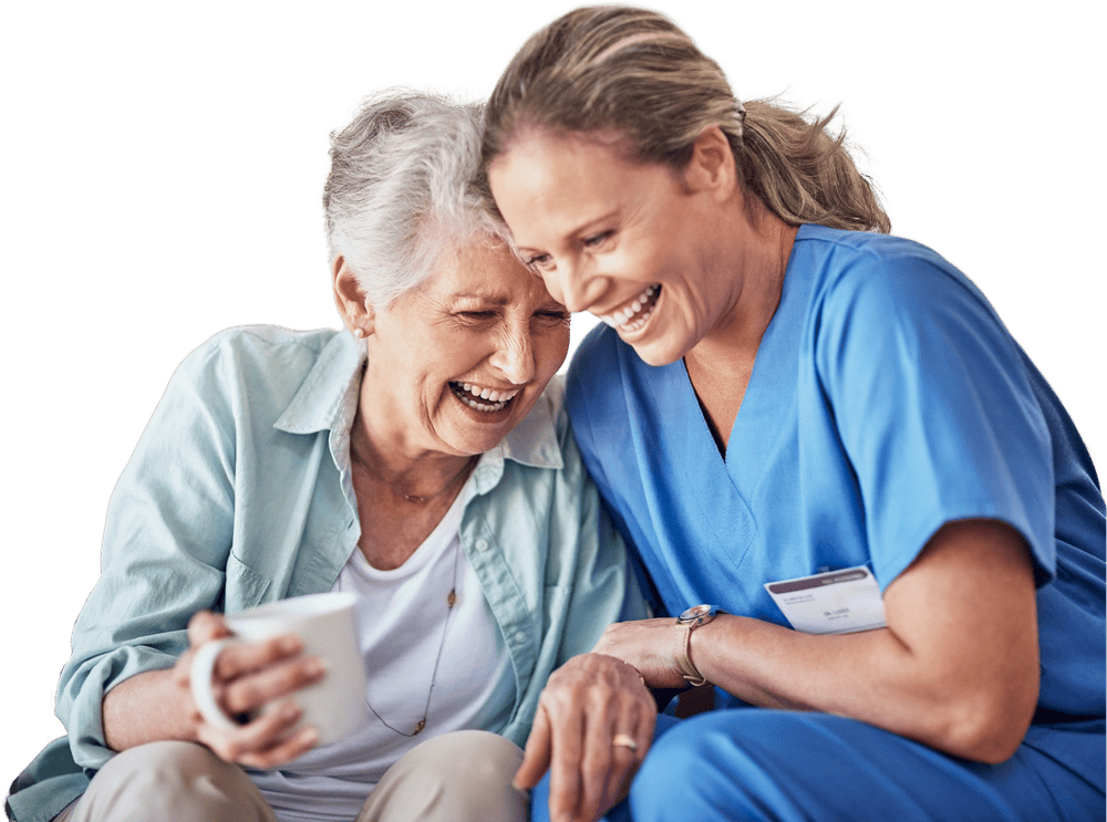 A nurse and an older woman laughing together over a cup of coffee